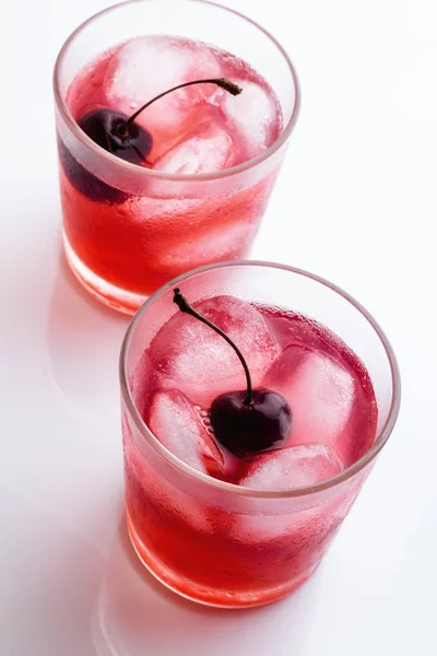 Red drink with a cherry in a glass with ice — Stock Photo, Image