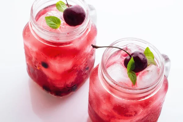 İki bardak beyaz zemin üzerine kırmızı içki ve buz yakın ile cam