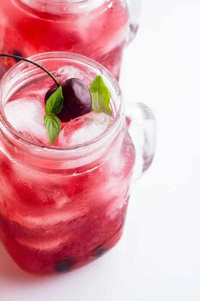 Glass mug with red drink, berries and ice on a white background — Stock Photo, Image