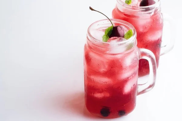 Twee glazen mokken met een rode drank en ijs op een witte achtergrond — Stockfoto