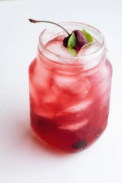 Red drink with ice, cherries and basil on a white background — Stock Photo, Image