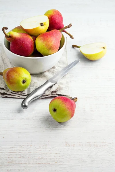 Pêras vermelhas em uma placa branca e uma mesa de faca e lugar para texto — Fotografia de Stock