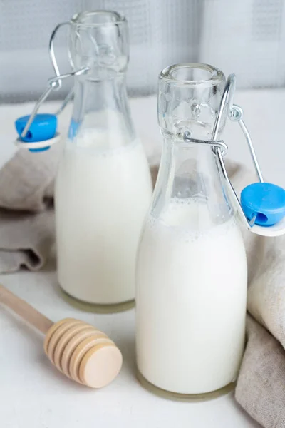 Milk in small glass bottles, honey and honey stic