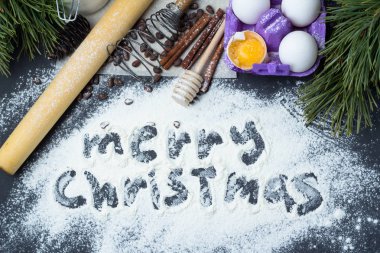 malzemeler ve aksesuarlar için Noel pişirme: un, yumurta, fındık, oklava, corolla, siyah bir zemin üzerine tarçın üstten görünüm, neşeli Noel, çam dalları ve koniler en iyi görünümünün un üzerinde yazıt