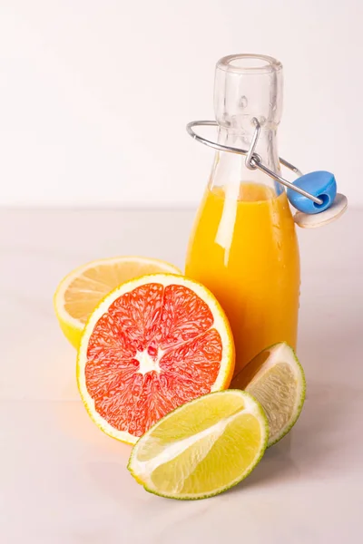 bottle with citrus juice and fruits on a white background