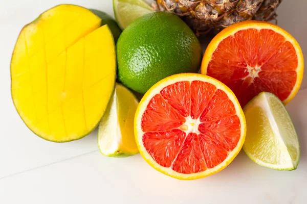 mango, pineapple and citrus fruits close up on white