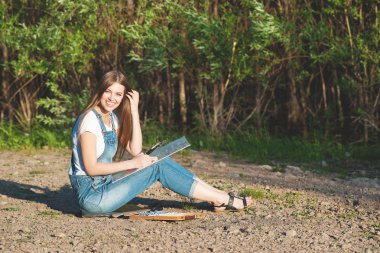 Genç güzel kadın sanatçı boya Sunset'teki Nehri kıyısında.