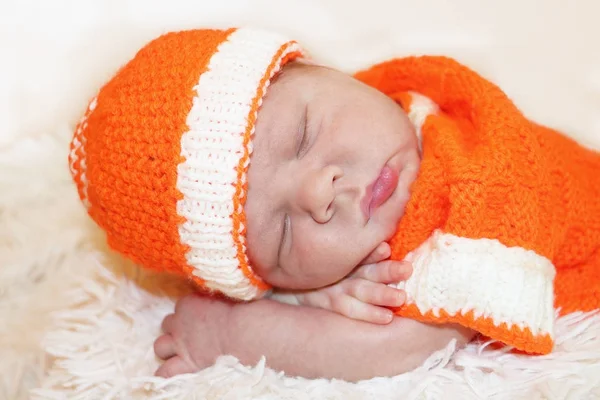 Lindo bebé recién nacido dormido tranquilo vestido con una naranja de punto — Foto de Stock