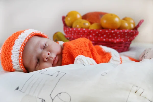 Lindo bebé recién nacido dormido vestido con un traje de punto naranja w — Foto de Stock