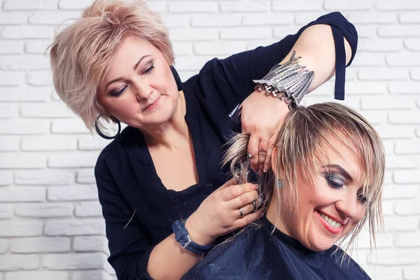 Парикмахер стрижет волосы женщины — стоковое фото