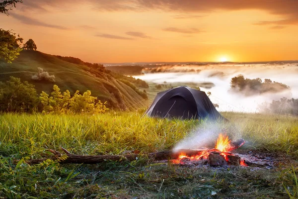 campfire and tent at sunrise