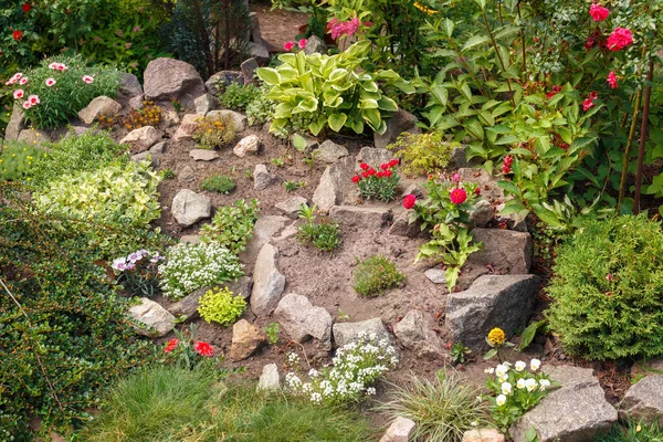 Jardín de flores con plantas frescas y piedras — Foto de Stock