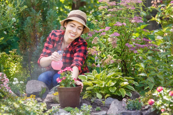 Giardiniere spruzzando acqua sui fiori — Foto Stock