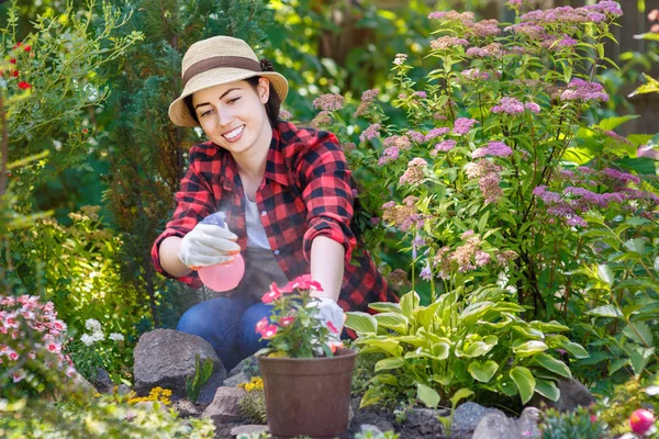 Giardiniere spruzzando acqua sui fiori — Foto Stock