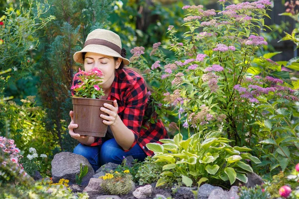 Jardinero chica oliendo flores en el jardín —  Fotos de Stock