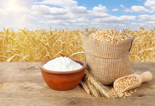 Grãos de trigo e farinha na mesa — Fotografia de Stock