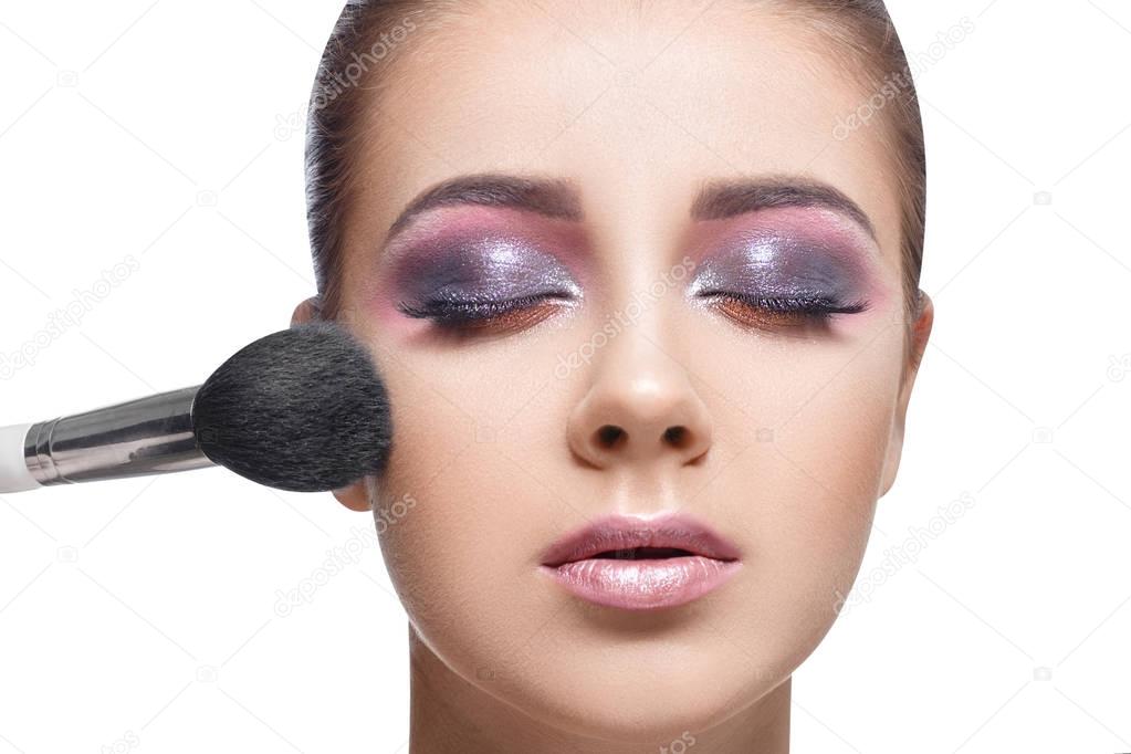 girl applying cosmetic using makeup brush