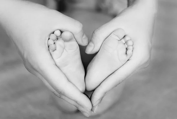 Tacones del recién nacido en las manos de la madre formando un corazón —  Fotos de Stock