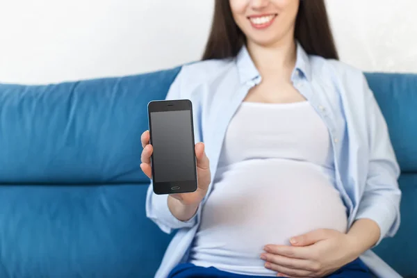 Mujer embarazada sosteniendo el teléfono con pantalla vacía — Foto de Stock