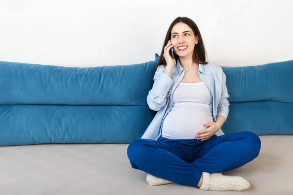 Беременная женщина звонит на смартфон — стоковое фото