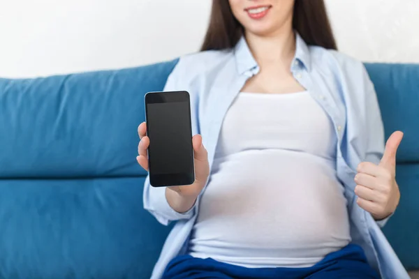Mujer embarazada sosteniendo el teléfono con pantalla vacía — Foto de Stock