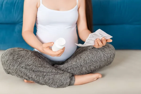 Donna incinta con in mano un flacone di pillole — Foto Stock