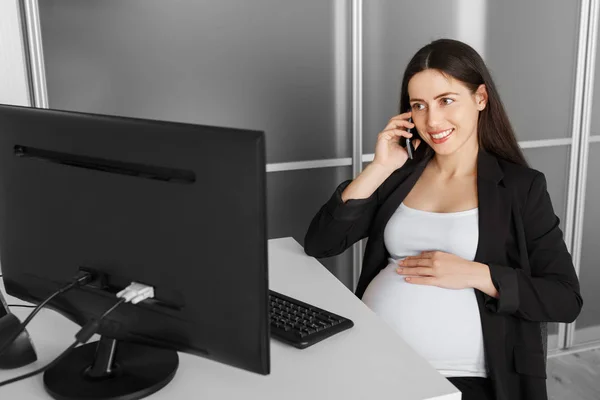 Pregnant woman talking on the phone in the office Stock Photo