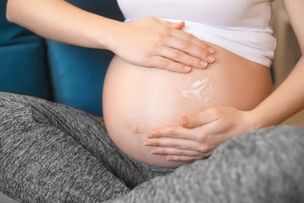 Mujer embarazada aplicando crema en su vientre — Foto de Stock