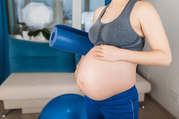 Беременная женщина с ковриком для йоги — стоковое фото