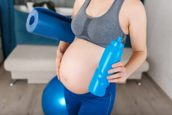Kobieta w ciąży z matę do jogi i butelka wody — Zdjęcie stockowe
