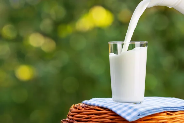Mjölk från jug hälla i glas — Stockfoto