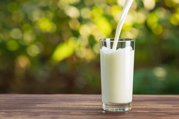 Milk pouring into glass — Stock Photo, Image