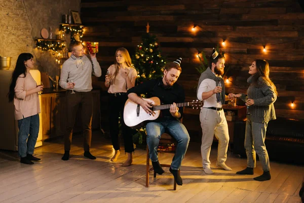 Group of young man and woman sings at a Christmas party in cozy house