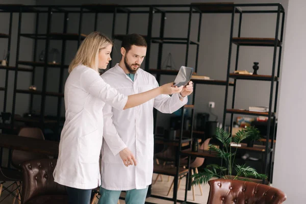 Medical team of two young doctors discuss X-ray of patient in meeting room