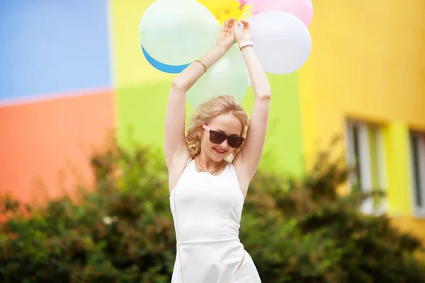 Hermosa rubia joven con un humor alegre Bailando en la calle con bolas de colores . —  Fotos de Stock