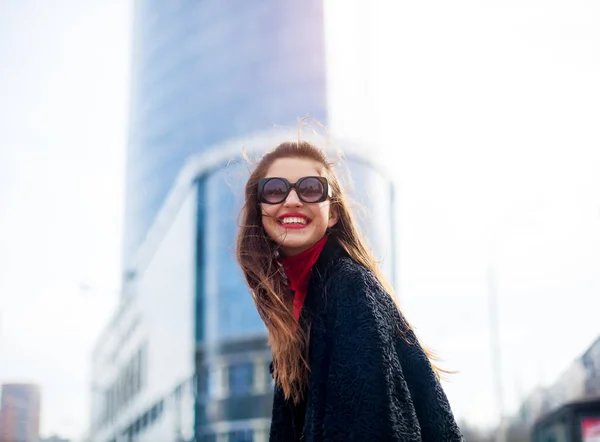 Chica expresiva con el pelo largo divirtiéndose en la ciudad.Ella lleva gafas de sol y sonriendo a la cámara con una sonrisa blanca como la nieve . —  Fotos de Stock