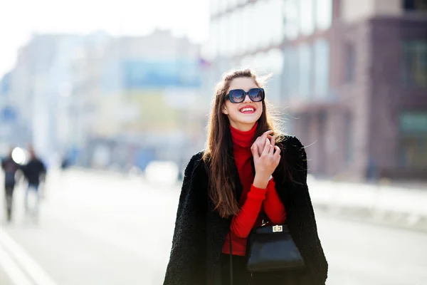 Utomhus livsstil närbild porträtt av glad ung kvinna i snygg casual outfit stående på gatan. Hon ler och ser på kameran — Stockfoto