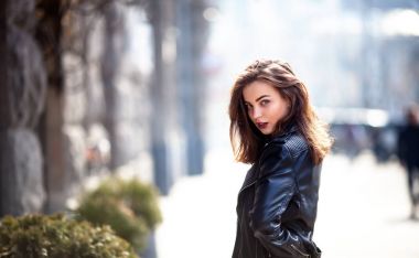 Uzun kıvırcık saçları arka bina on sokak kameraya gülümseyen etkili kız closeup portresi