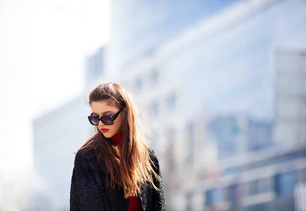 Vonzó, modern nő állt a város utcája. Divatos fiatal nő visel, napszemüveget, fekete ing, kabát . — Stock Fotó
