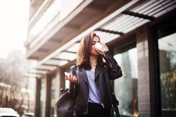 Närbild av mode gatan stil porträtt av en vacker flicka i en casual outfit promenader i staden. Vackra brunett dricka kaffe — Stockfoto