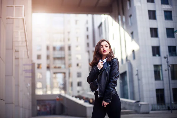 Mode hipster kvinna poserar utomhus. läder jacka, brunett hår, röda läppar, solglasögon. Street fashion-konceptet. — Stockfoto