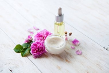 Beyaz ahşap arka plan Spa ayarı nemlendirici krem güzel pembe Gül ve gül özü yağı tencere ile Spa Tema nesneler üzerinde