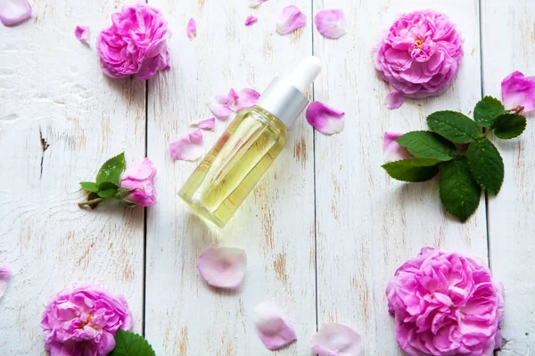 Biologische cosmetica met roos essentie olie op witte houten achtergrond kuur. Wellness massage — Stockfoto