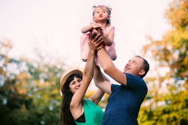 Babası omuzlarında uçan çocuk. mutlu aile kavramı - baba, anne ve çocuk kızı eğleniyor ve doğada oynamaya.