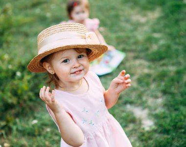 Şirin Bebek kız portre. Hasır şapkalı küçük kız gülümsüyor ve kameraya benziyor