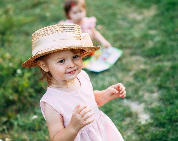 Küçük kızlar doğa şirin bebek kız portre oynuyorlar. Metin için yer hasır şapkalı küçük kız gülümsüyor