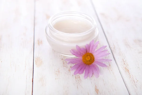 Olla de crema hidratante para la cara y hermosa flor sobre un fondo de madera blanca. facial cosmética orgánica natural. De cerca. —  Fotos de Stock