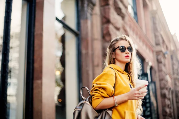 Outdoor waist up portrait of young beautiful woman with long hair. Model wearing stylish sunglasses, clothes, holding bag. City lifestyle. — Stock Photo, Image