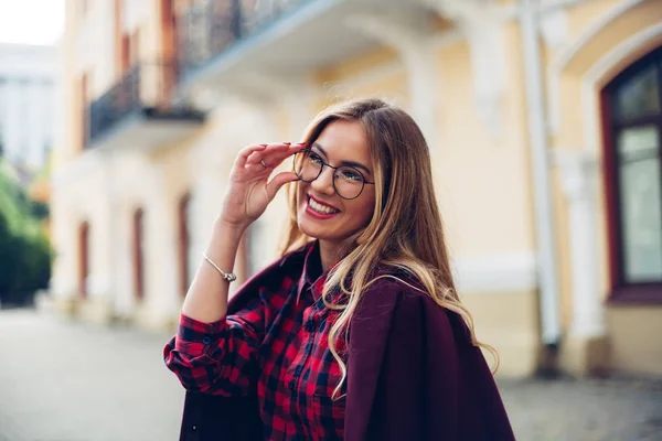 Cheerful pretty young lady holds his glasses her hands and smiles at his interlocutor. — Stock Photo, Image