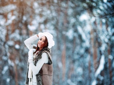 Açık kar taneleri altında kış ormandaki eğleniyor Beyaz giysili güzel kızı.